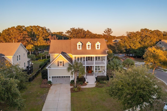 view of front of home with a front lawn, concrete driveway, covered porch, a balcony, and a garage