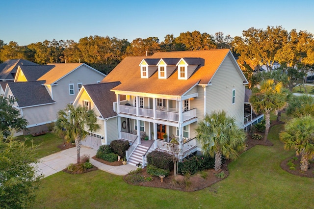 view of front of property featuring a balcony, a porch, concrete driveway, and a front lawn