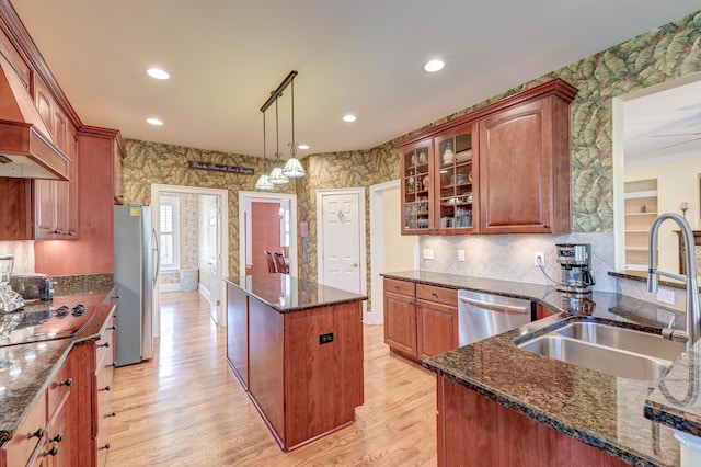 kitchen with sink, decorative light fixtures, a center island, appliances with stainless steel finishes, and dark stone counters