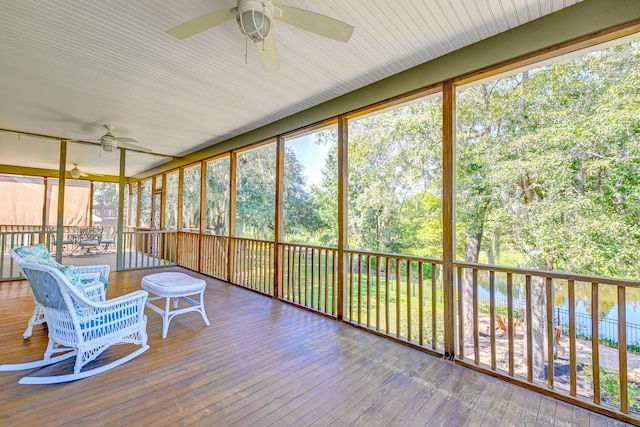 unfurnished sunroom featuring a water view, ceiling fan, and a healthy amount of sunlight