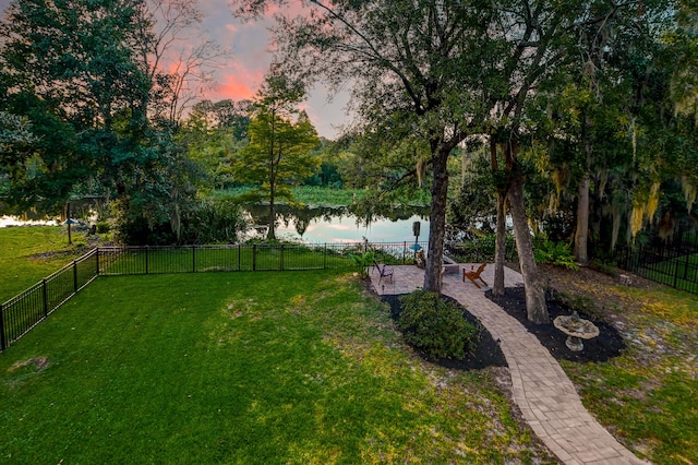 yard at dusk featuring a water view