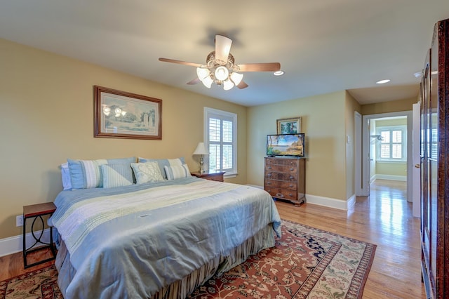 bedroom featuring multiple windows, ceiling fan, and light hardwood / wood-style flooring