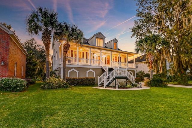 back house at dusk with a porch and a lawn