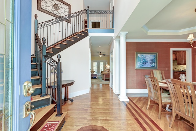 entryway with ornate columns, hardwood / wood-style flooring, ceiling fan, a tray ceiling, and crown molding