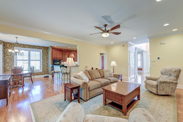 living room with ornamental molding, ceiling fan with notable chandelier, and light wood-type flooring