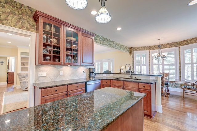 kitchen featuring hanging light fixtures, sink, stainless steel dishwasher, and dark stone counters