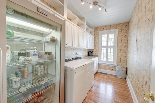 washroom featuring cabinets, rail lighting, washer and dryer, and light hardwood / wood-style floors