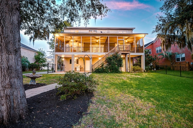 back house at dusk with a balcony and a lawn