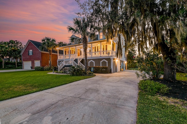 view of front of property featuring a yard, a garage, and a porch