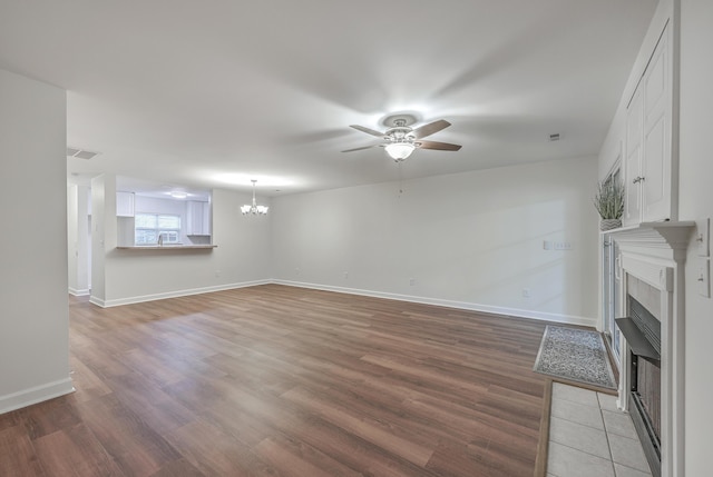 unfurnished living room with ceiling fan with notable chandelier and hardwood / wood-style floors