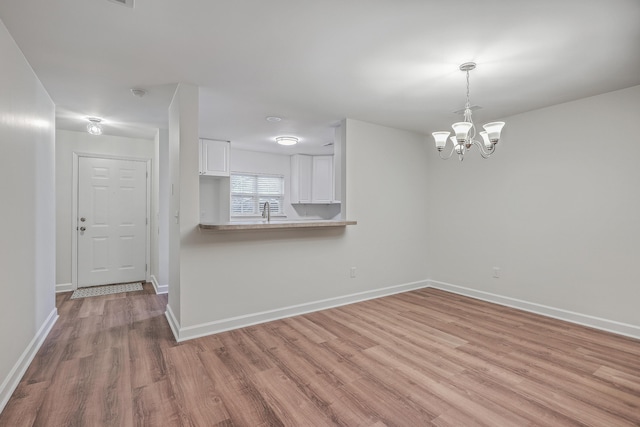 spare room featuring light hardwood / wood-style floors, sink, and a chandelier