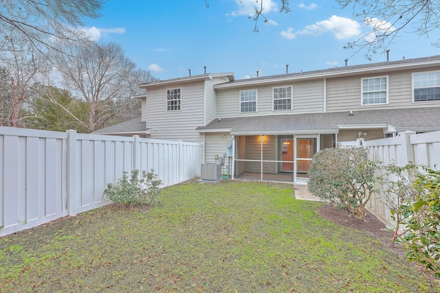 back of property with central AC unit, a sunroom, and a yard