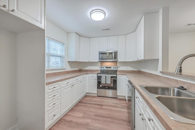 kitchen with sink, white cabinetry, light hardwood / wood-style flooring, and stainless steel appliances