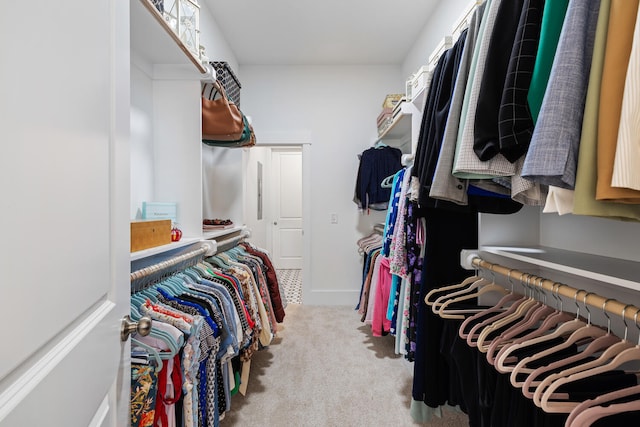 walk in closet with light carpet