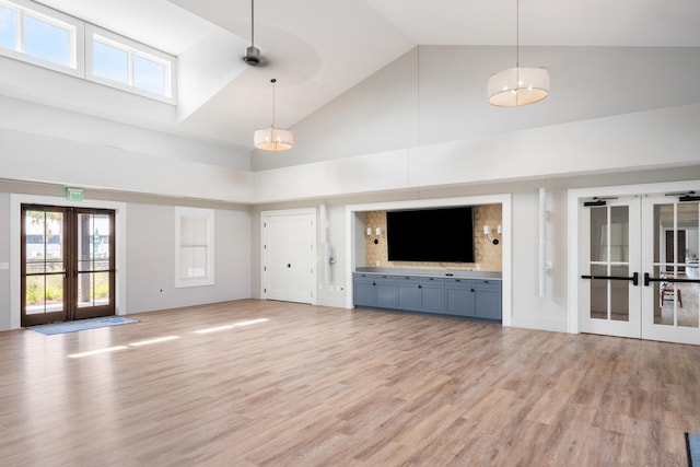 unfurnished living room featuring french doors, high vaulted ceiling, and light hardwood / wood-style flooring