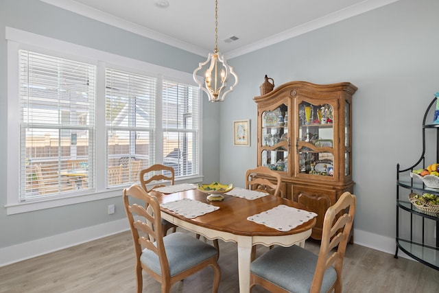 dining room with light hardwood / wood-style flooring, ornamental molding, and a chandelier