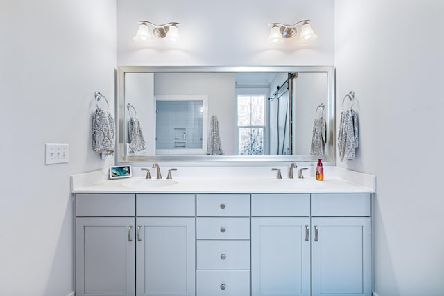 bathroom featuring double vanity, a shower with door, and a sink