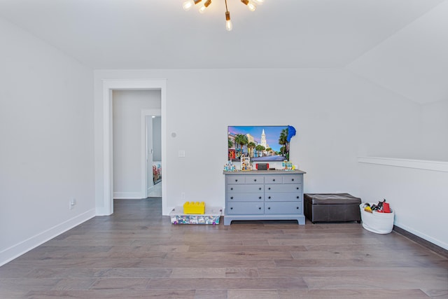 interior space featuring lofted ceiling, an inviting chandelier, wood finished floors, and baseboards