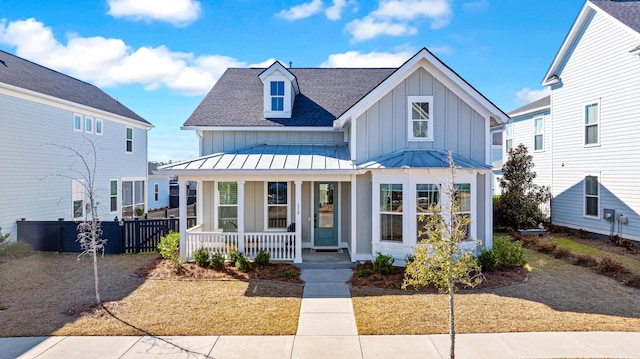 view of front of house featuring a standing seam roof, covered porch, a shingled roof, fence, and board and batten siding