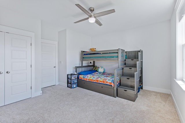 carpeted bedroom with ceiling fan, multiple windows, and baseboards