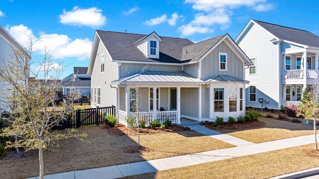 view of front of property featuring a shingled roof, covered porch, board and batten siding, metal roof, and fence