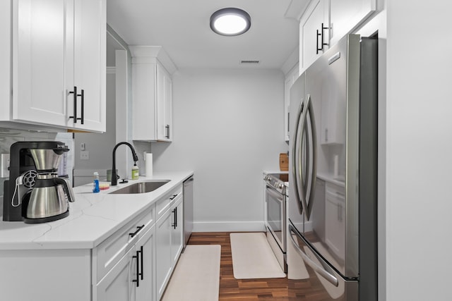 1990 Butternut St, Charleston, SC 29414 - kitchen featuring appliances with stainless steel finishes, dark wood finished floors, white cabinets, and light stone countertops