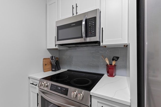 1990 Butternut St, Charleston, SC 29414 - kitchen featuring appliances with stainless steel finishes, white cabinetry, tasteful backsplash, and light stone counters