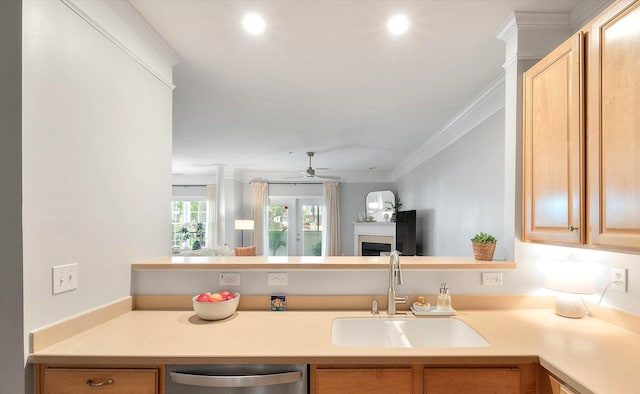 kitchen featuring crown molding, a sink, a fireplace, light countertops, and a ceiling fan