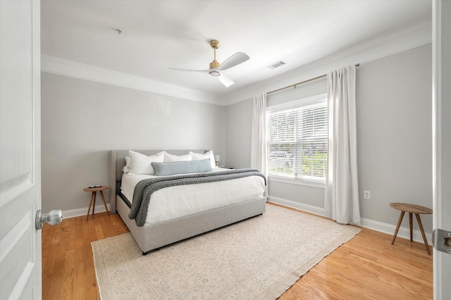 bedroom with baseboards, ornamental molding, light wood finished floors, and visible vents