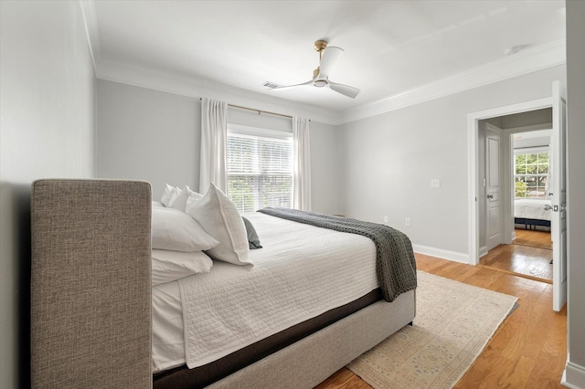 bedroom featuring crown molding, ceiling fan, light wood-style flooring, and visible vents