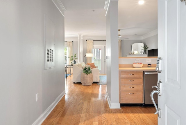 hall featuring crown molding, baseboards, and light wood finished floors