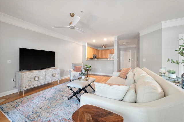 living area featuring baseboards, a ceiling fan, and ornamental molding