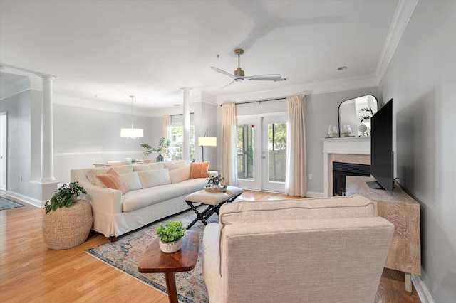 living room with crown molding, a ceiling fan, decorative columns, and wood finished floors