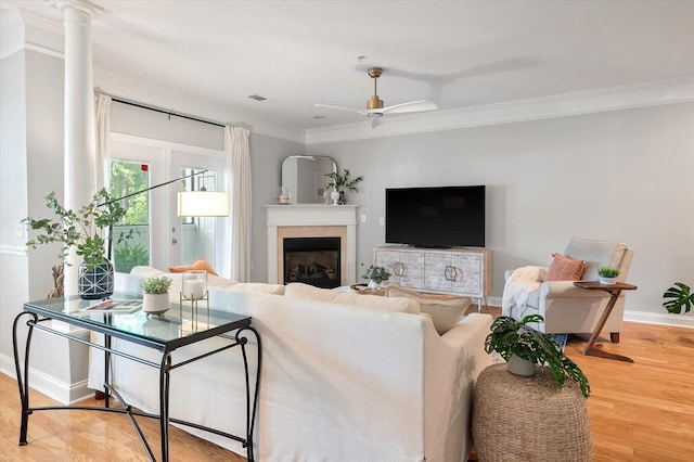 living area with crown molding, baseboards, a fireplace, and wood finished floors