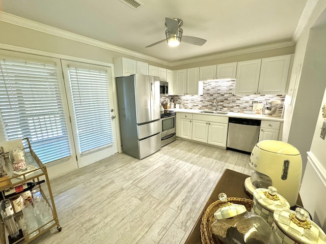 kitchen with crown molding, decorative backsplash, light wood-style flooring, appliances with stainless steel finishes, and a sink