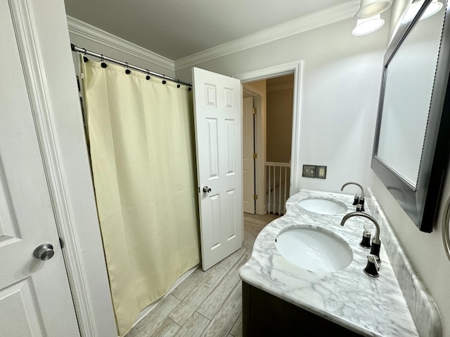 full bath with double vanity, wood finished floors, crown molding, and a sink