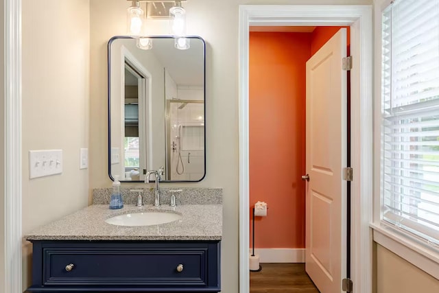 bathroom featuring vanity, wood-type flooring, a wealth of natural light, and a shower with shower door