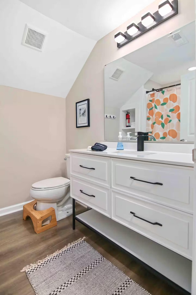 bathroom with vanity, lofted ceiling, hardwood / wood-style floors, and toilet