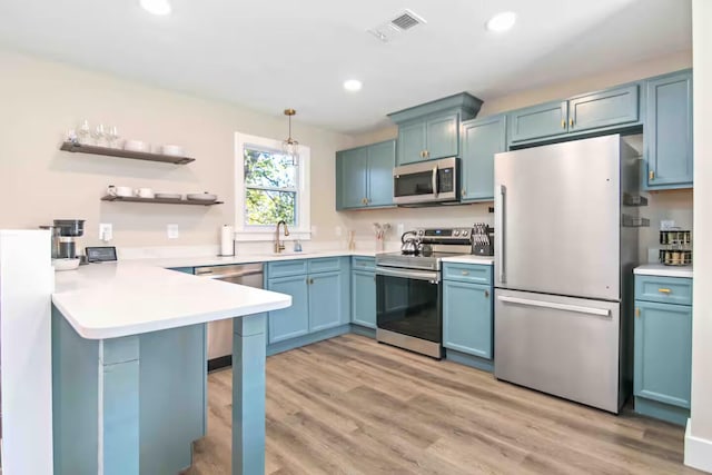 kitchen with appliances with stainless steel finishes, sink, hanging light fixtures, blue cabinetry, and light wood-type flooring