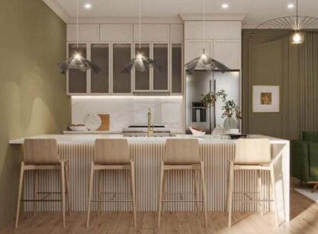 kitchen featuring a kitchen breakfast bar, light hardwood / wood-style floors, decorative backsplash, and a large island with sink