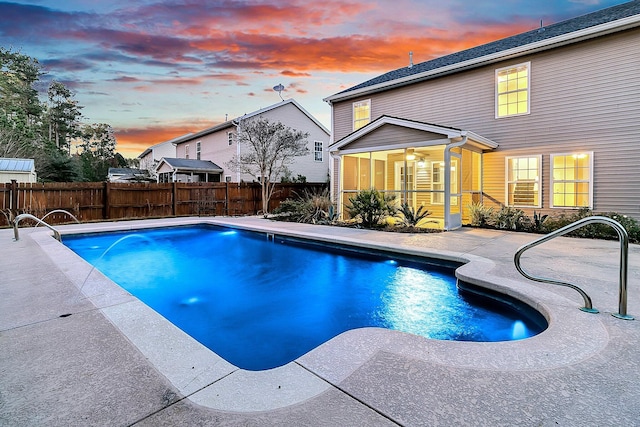 pool at dusk featuring a sunroom