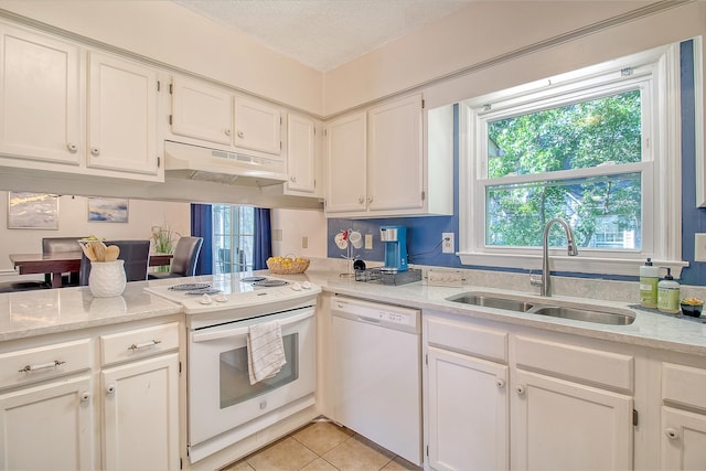 kitchen featuring white appliances, under cabinet range hood, a sink, white cabinetry, and light tile patterned floors