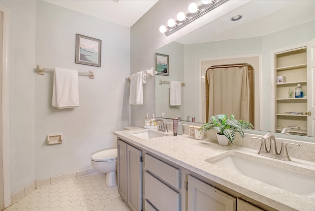 bathroom featuring toilet, baseboards, double vanity, and curtained shower