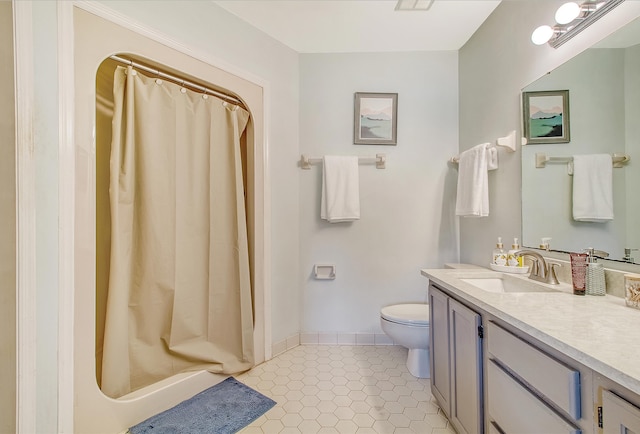 bathroom with toilet, vanity, a shower stall, tile patterned flooring, and baseboards