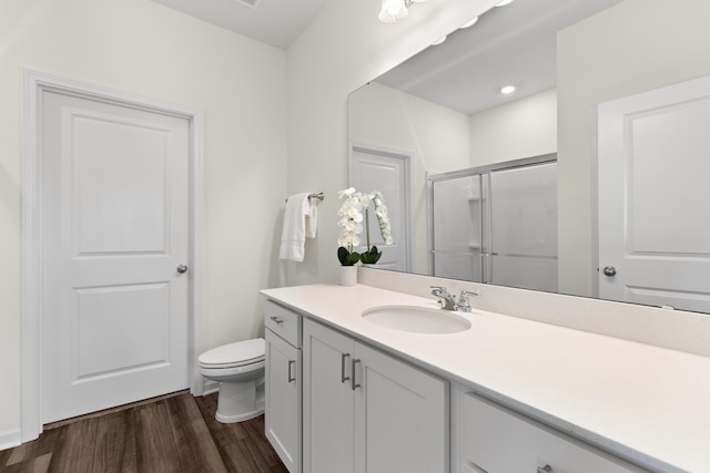 bathroom featuring vanity, toilet, hardwood / wood-style floors, and a shower with shower door