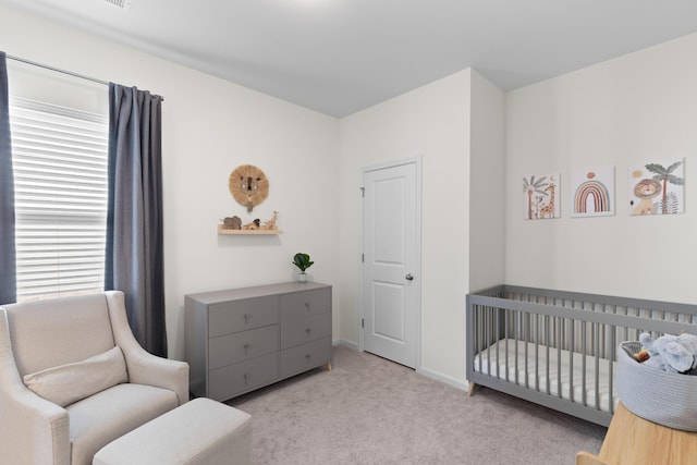 bedroom featuring a crib and light colored carpet