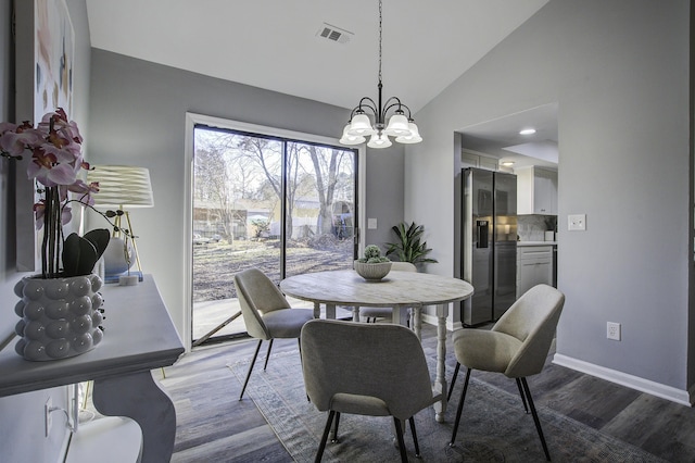 dining area featuring vaulted ceiling, a notable chandelier, and hardwood / wood-style flooring