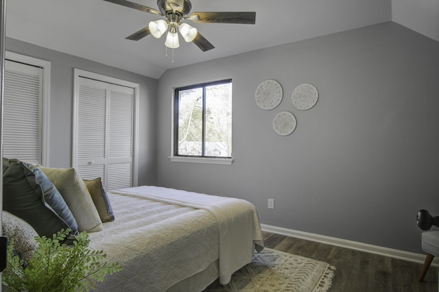 bedroom featuring ceiling fan, lofted ceiling, dark hardwood / wood-style floors, and two closets