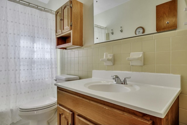 bathroom featuring vanity, toilet, walk in shower, and tile walls