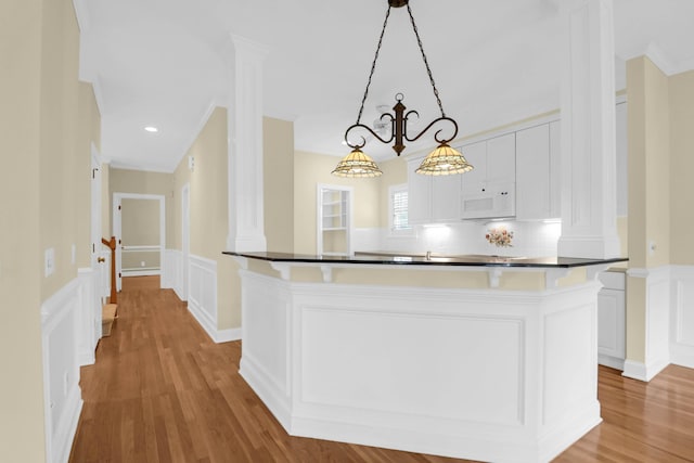 1025 Mathis Ferry Rd, Mount Pleasant, SC 29464 - kitchen with white microwave, light wood-style flooring, a decorative wall, white cabinetry, and wainscoting